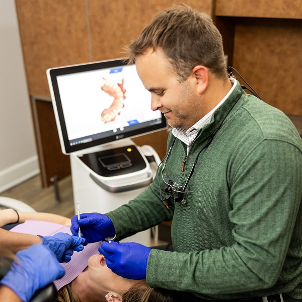 Dr. Kyle Burgmeier performing dental surgery on a female patient in a warm and welcoming office environment at Burgmeier Dentistry