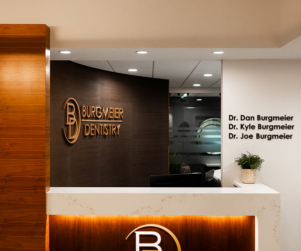 Warm and welcoming reception area at Burgmeier Dentistry featuring the office logo and decorative plants