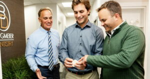 Two doctors talking to a patient about full-mouth dental implants